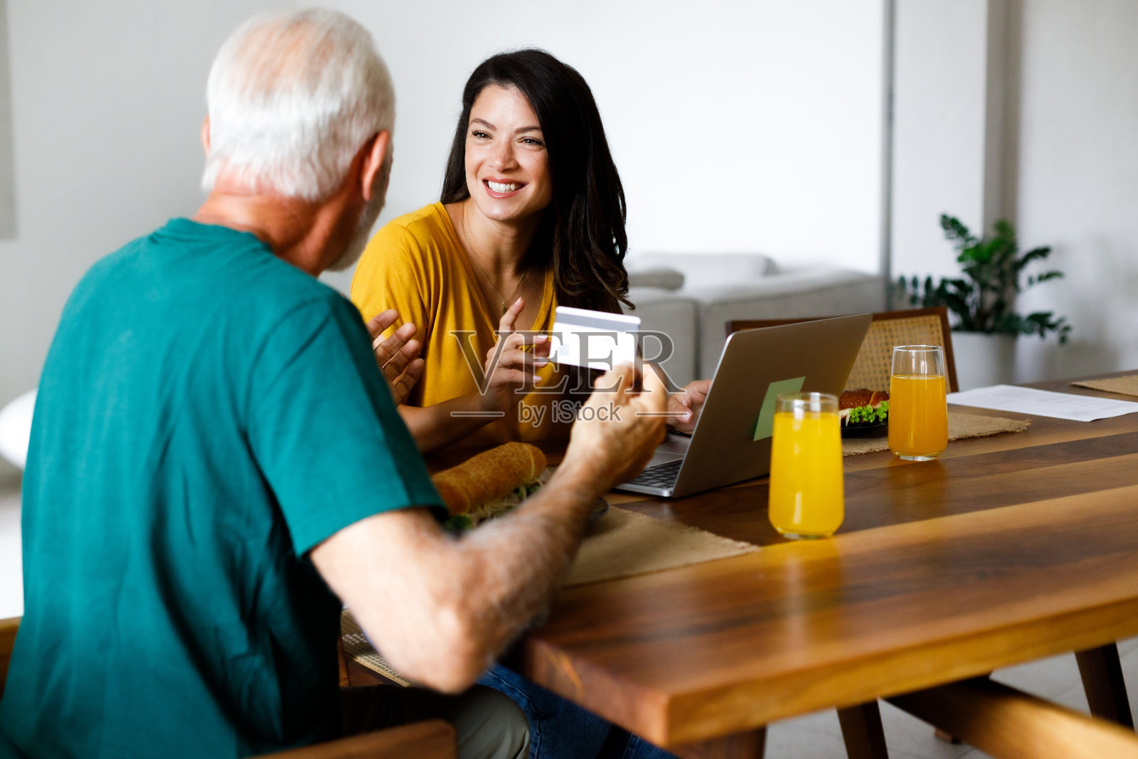 快乐的老年爸爸和成年女儿在家里享受网上购物的乐趣。照片摄影图片