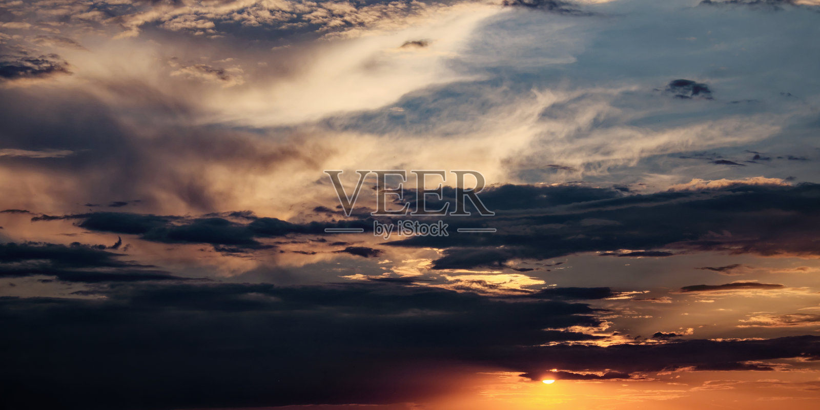 天空中乌云密布，日落时阳光灿烂。照片摄影图片