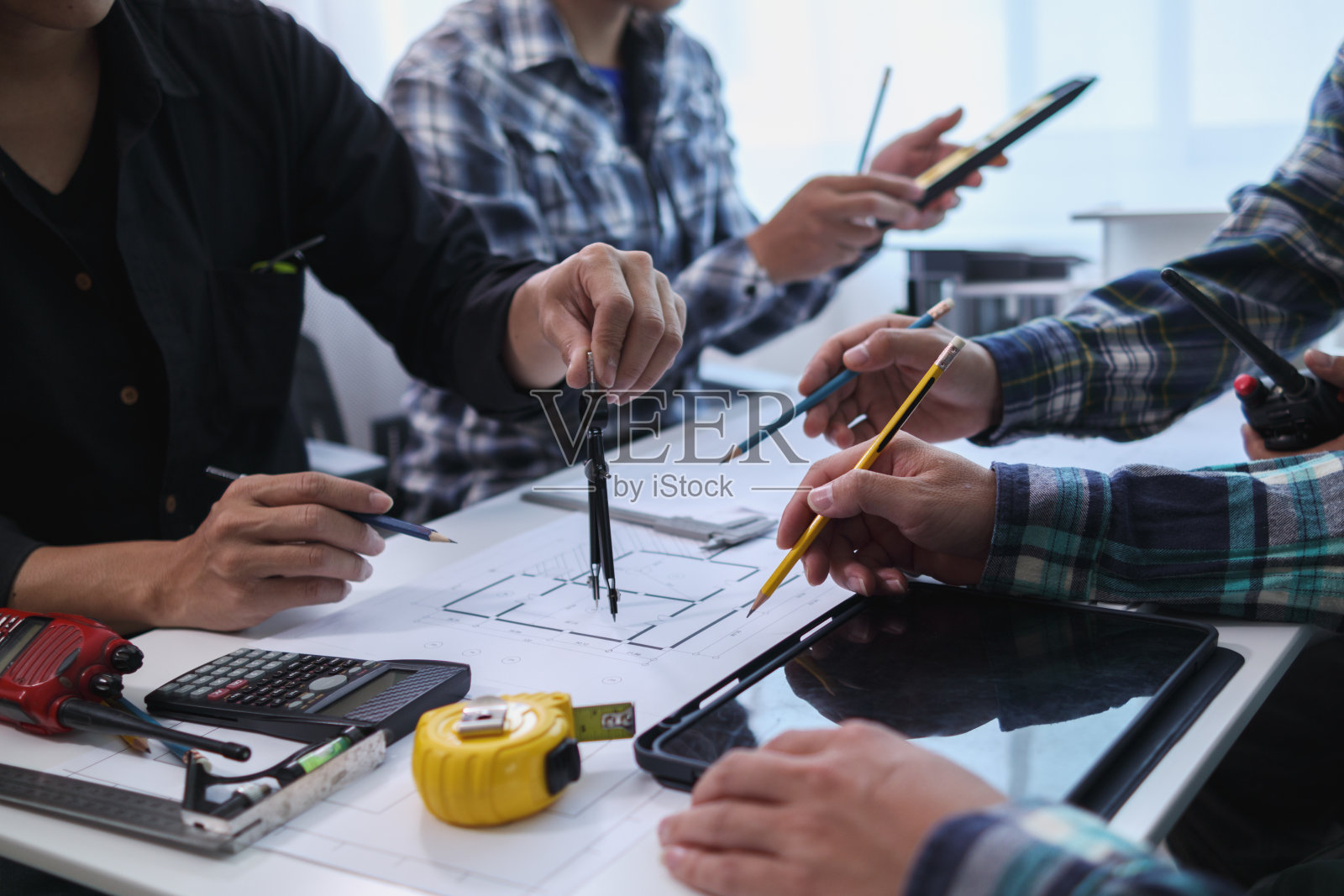 一个由工程师和建筑师组成的团队讨论房屋规划设计并估算建筑价格以适应建筑预算。与工程师和建筑师团队一起检查蓝图和文件照片摄影图片