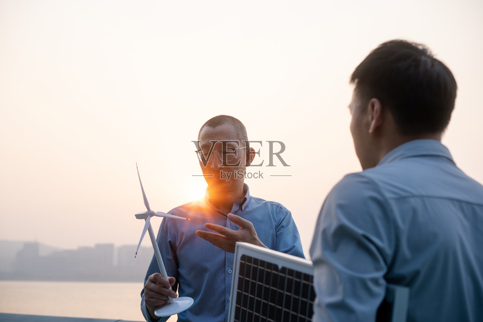 商务人士在江边手持太阳能电池板照片摄影图片