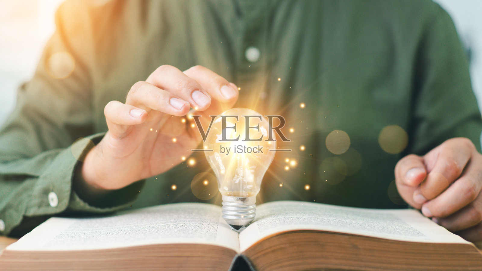 用手触摸灯泡或灯泡，思考教科书上的想法或未来的新想法。理念，自学，学习理念。读书、求知、寻找新思想的思想。照片摄影图片