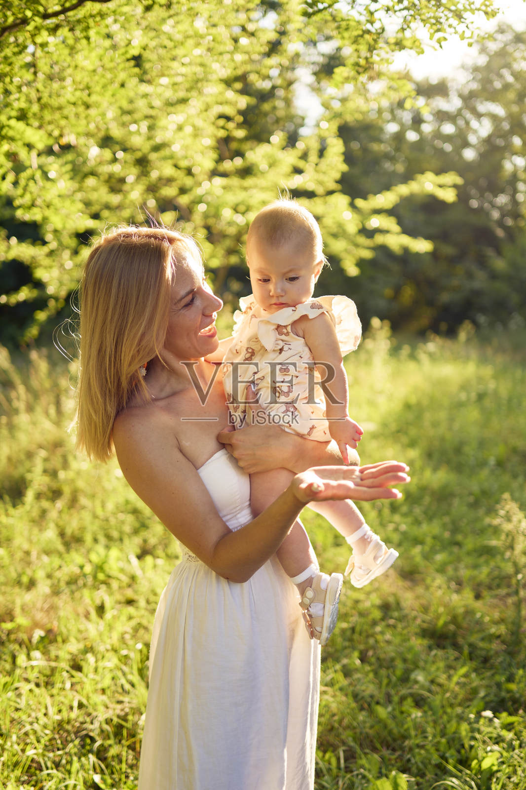 一位母亲和她的小女儿在阳光明媚的花园里玩耍照片摄影图片