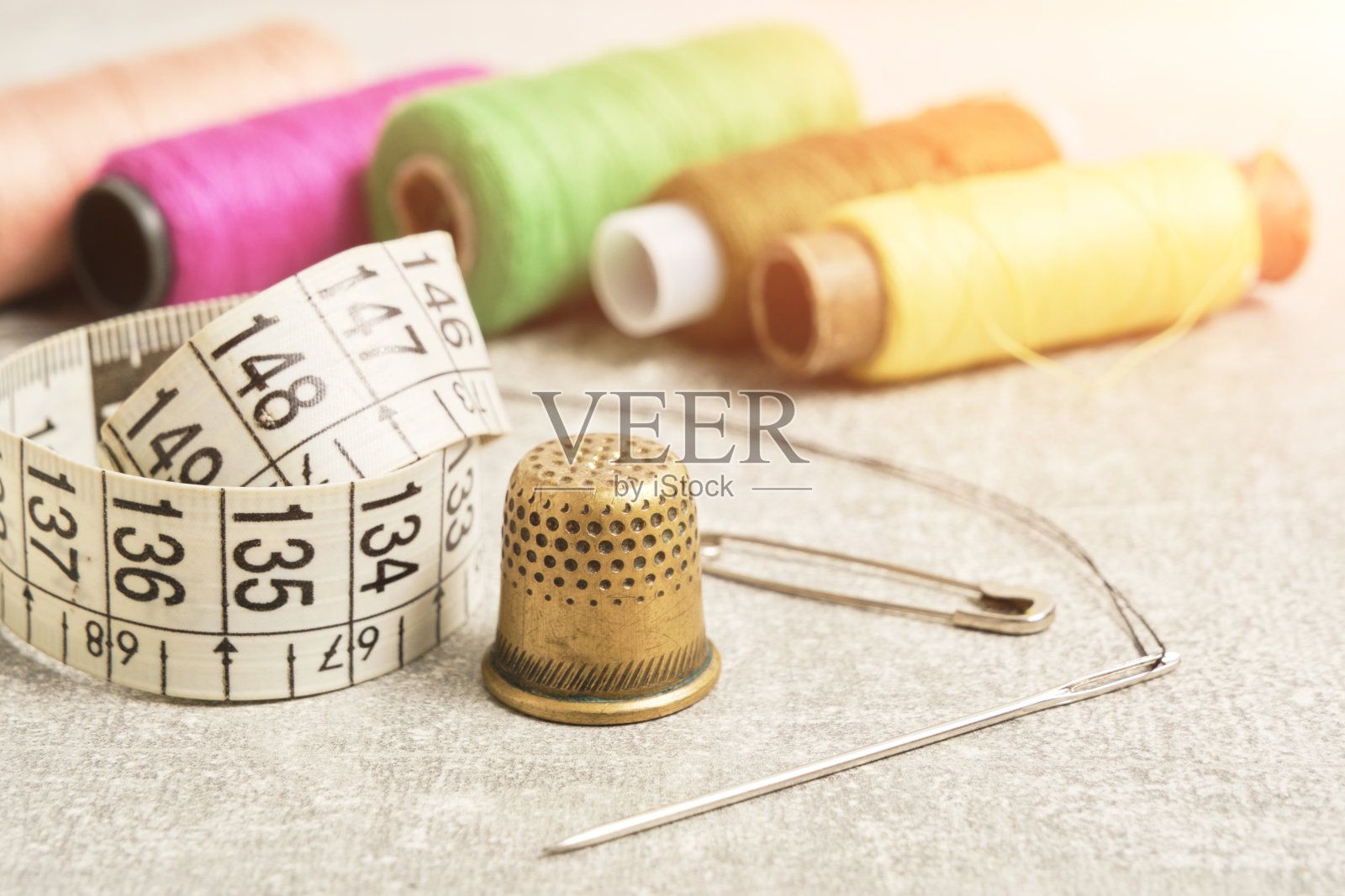 缝纫包:针、顶针、线和量具。灰色的混凝土桌面。照片摄影图片