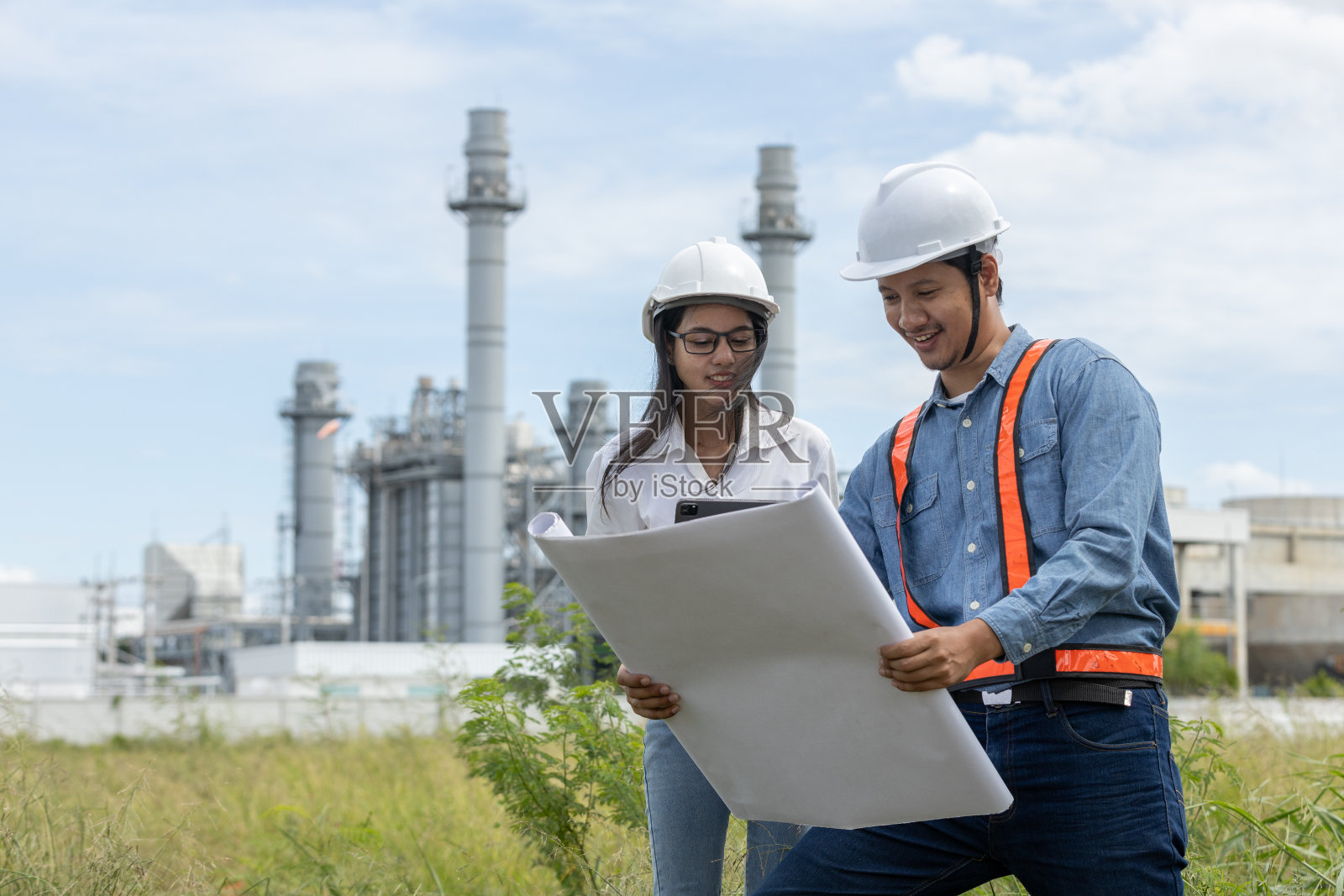 有图纸和图纸的工程师在生产电力、石油和能源的工厂工作。石化企业炼油厂施工经理。在发电厂工作的产业工人照片摄影图片