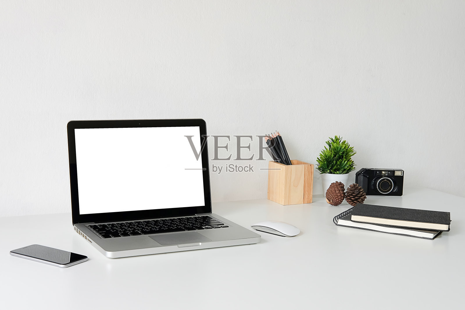 笔记本电脑和设备在桌子上对着白墙的特写照片摄影图片