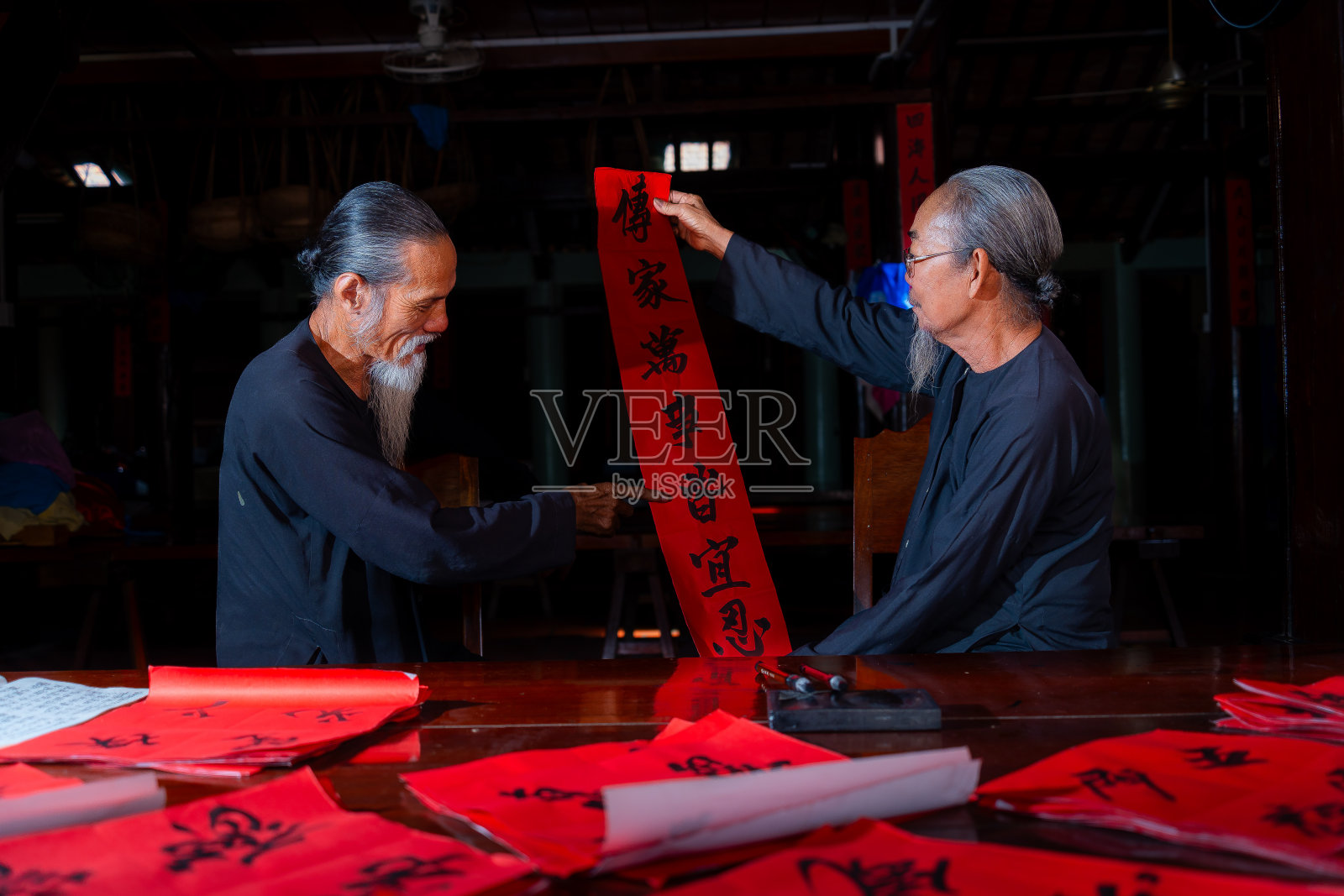老书生在中国农历新年写春联。春联是中国春节期间的一项流行传统。照片中的文字意味着新年快乐，平平安安。照片摄影图片