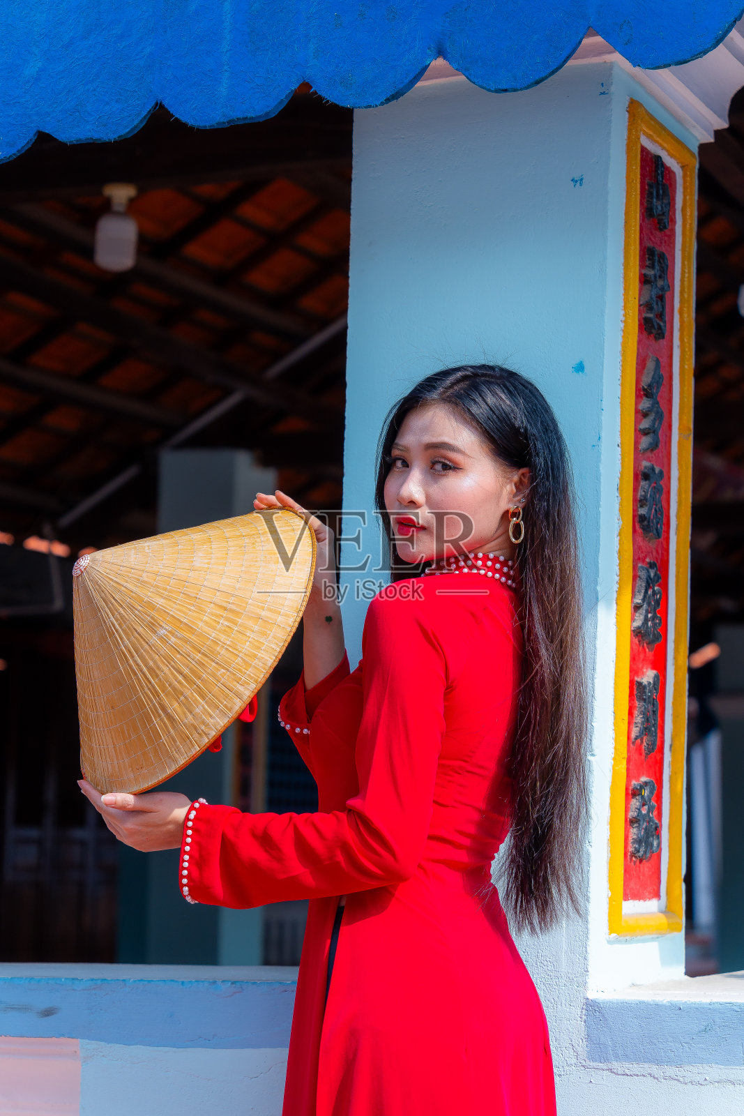 越南女孩穿着敖黛服装站在越南传统的房子里。照片中的文字代表着对家人、幸福、成功、健康的美好祝愿。春节和新年。照片摄影图片