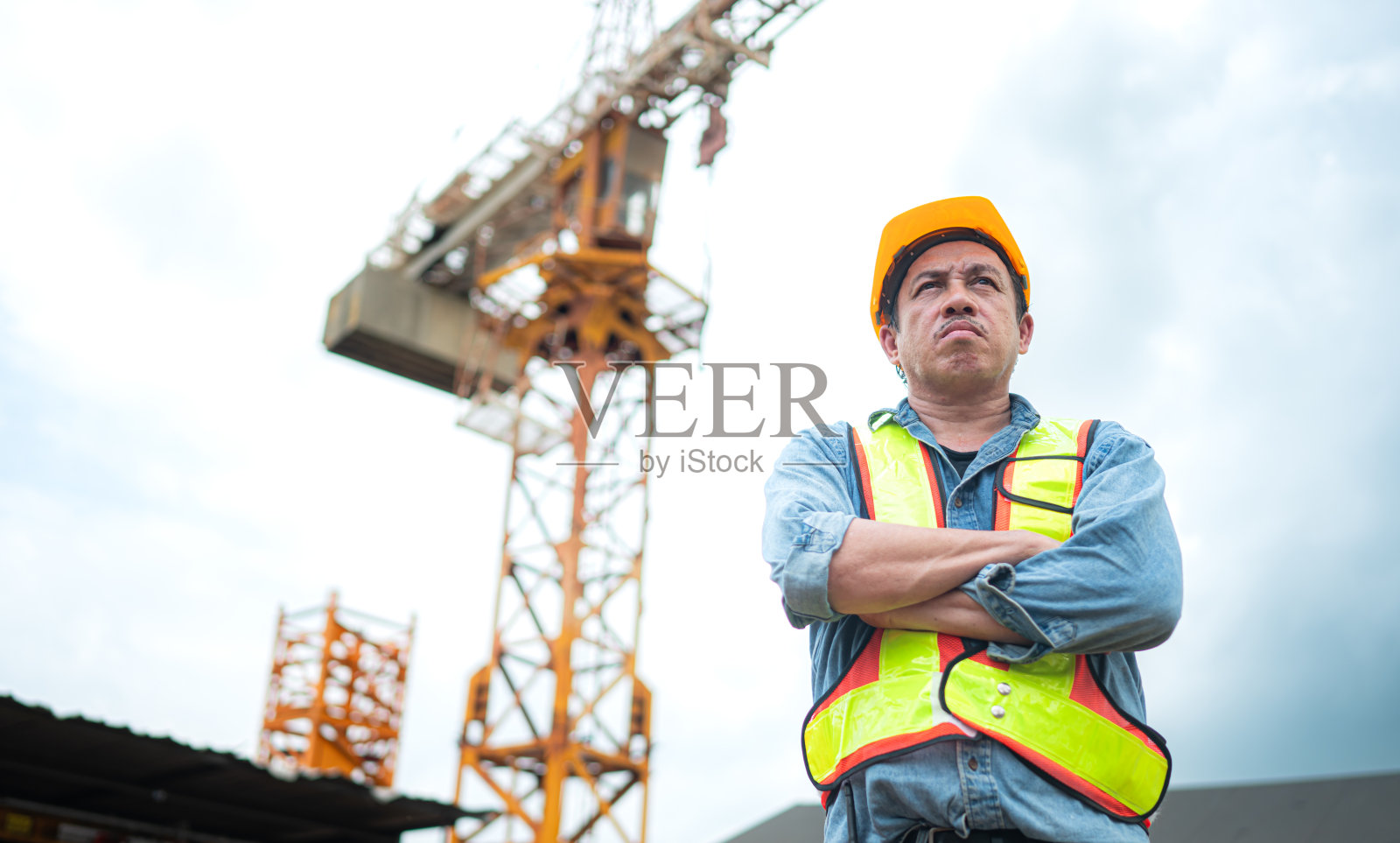 起重机工人肖像使用对讲机与塔式起重机操作员通信，以提升和移动建筑工地上的物体照片摄影图片