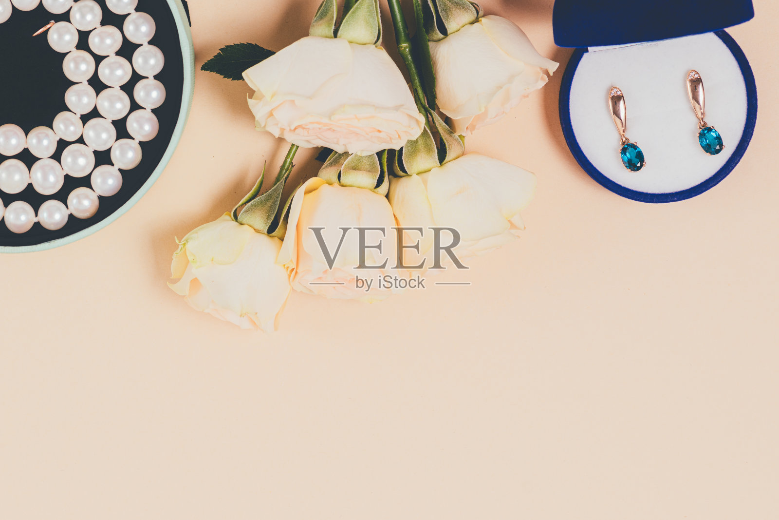 桌子上放着一束白玫瑰，旁边是一个装有耳环的蓝盒子照片摄影图片