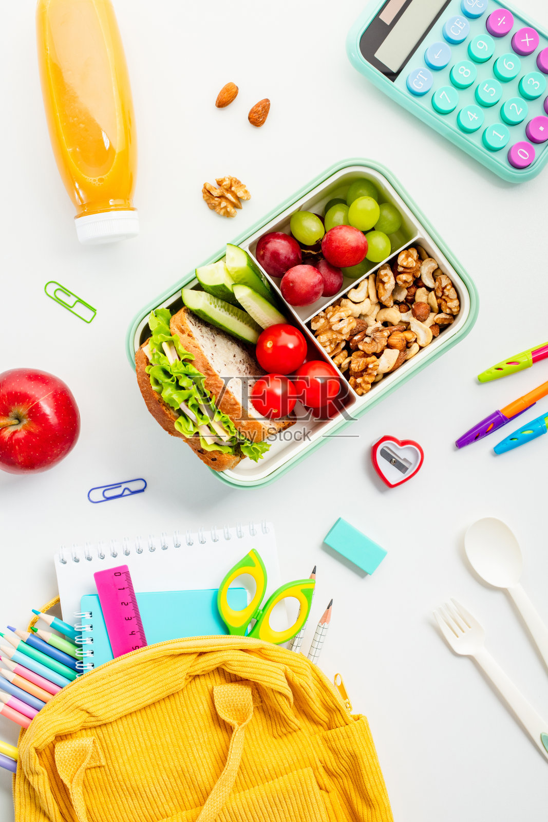 有营养的午餐盒，里面有三明治和水果，学习用品，还有一个亮黄色的背包，背景是干净的白色。适合教育和返校主题照片摄影图片