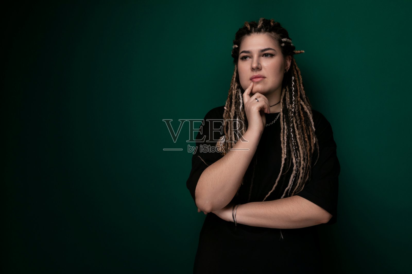 扎着脏辫的女人站在绿墙前照片摄影图片