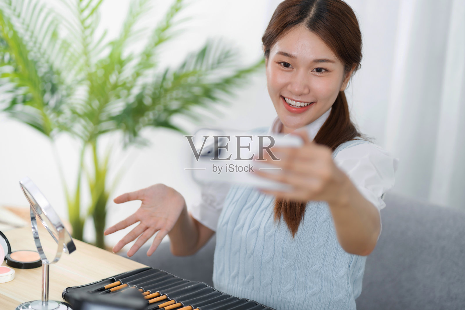 美博主。快乐的亚洲视频博主正在展示化妆品productsÂ，为她的美容博客提供建议照片摄影图片