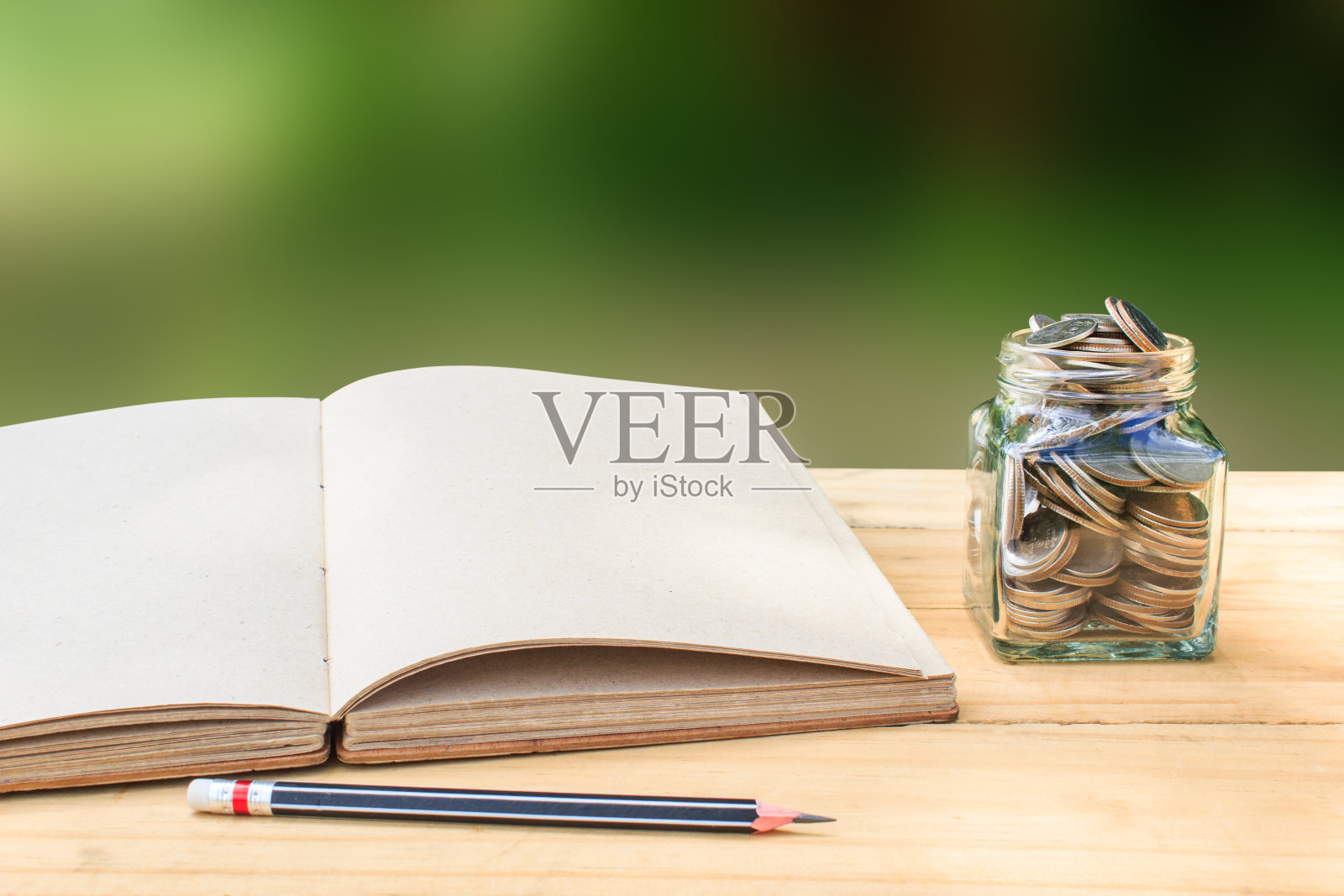 桌子上坛子里的硬币，书和笔的特写照片摄影图片