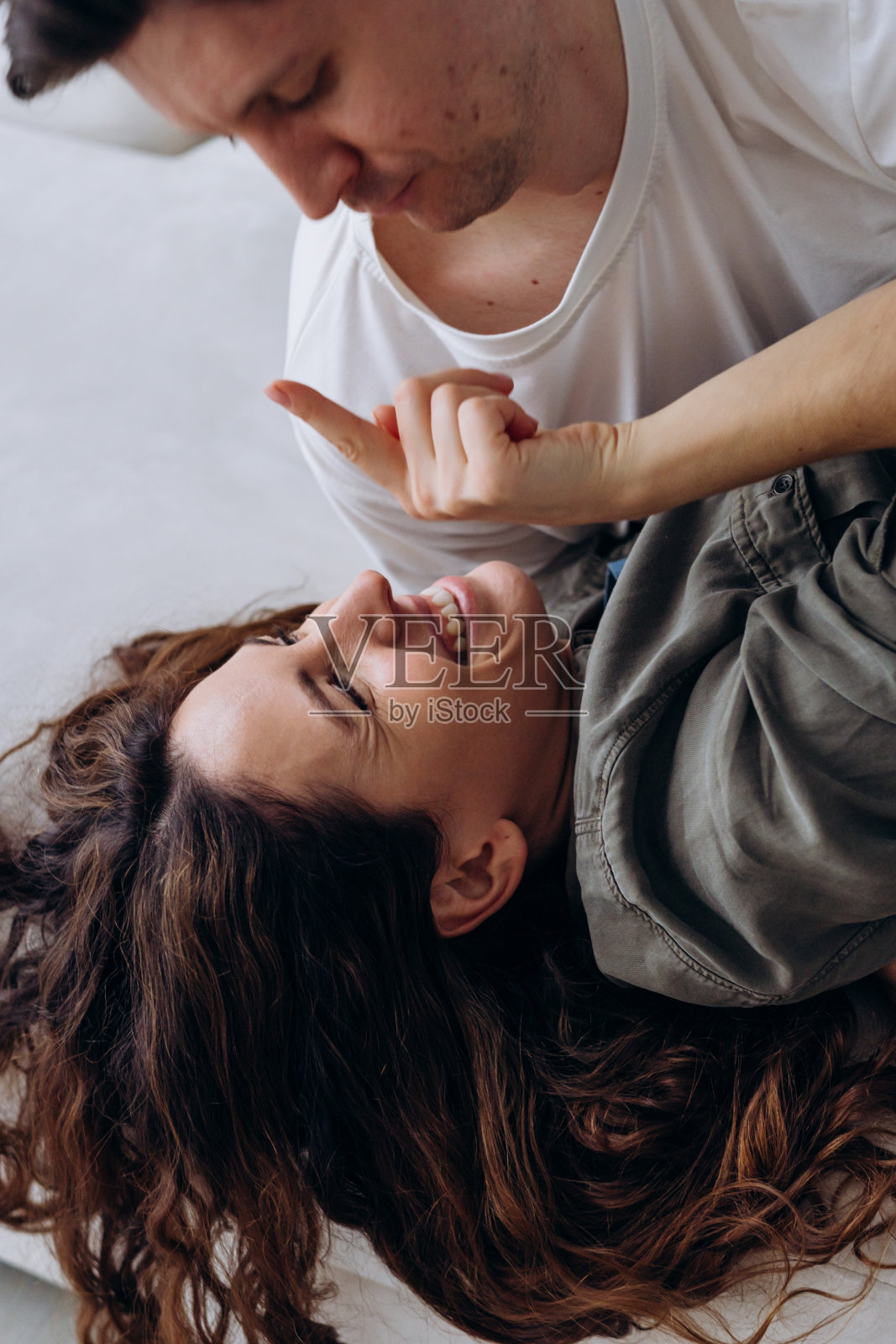 一个快乐的时刻，当一个女人躺着笑着与一个男人开玩笑的互动，突出了深厚的联系和共享的幸福。照片摄影图片