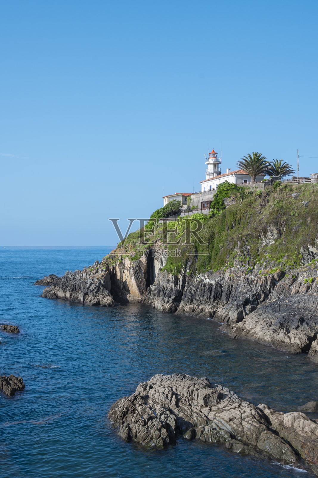 在西班牙库迪列罗镇的岩石上，垂直拍摄美丽的海上灯塔照片摄影图片