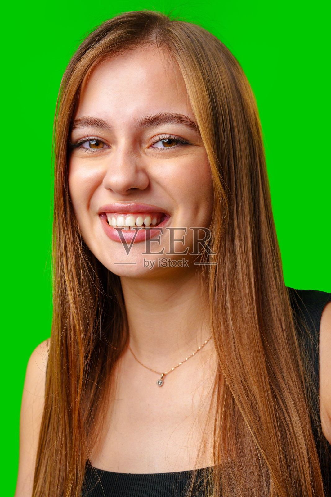年轻女子微笑着，棕色长发映衬着绿幕照片摄影图片