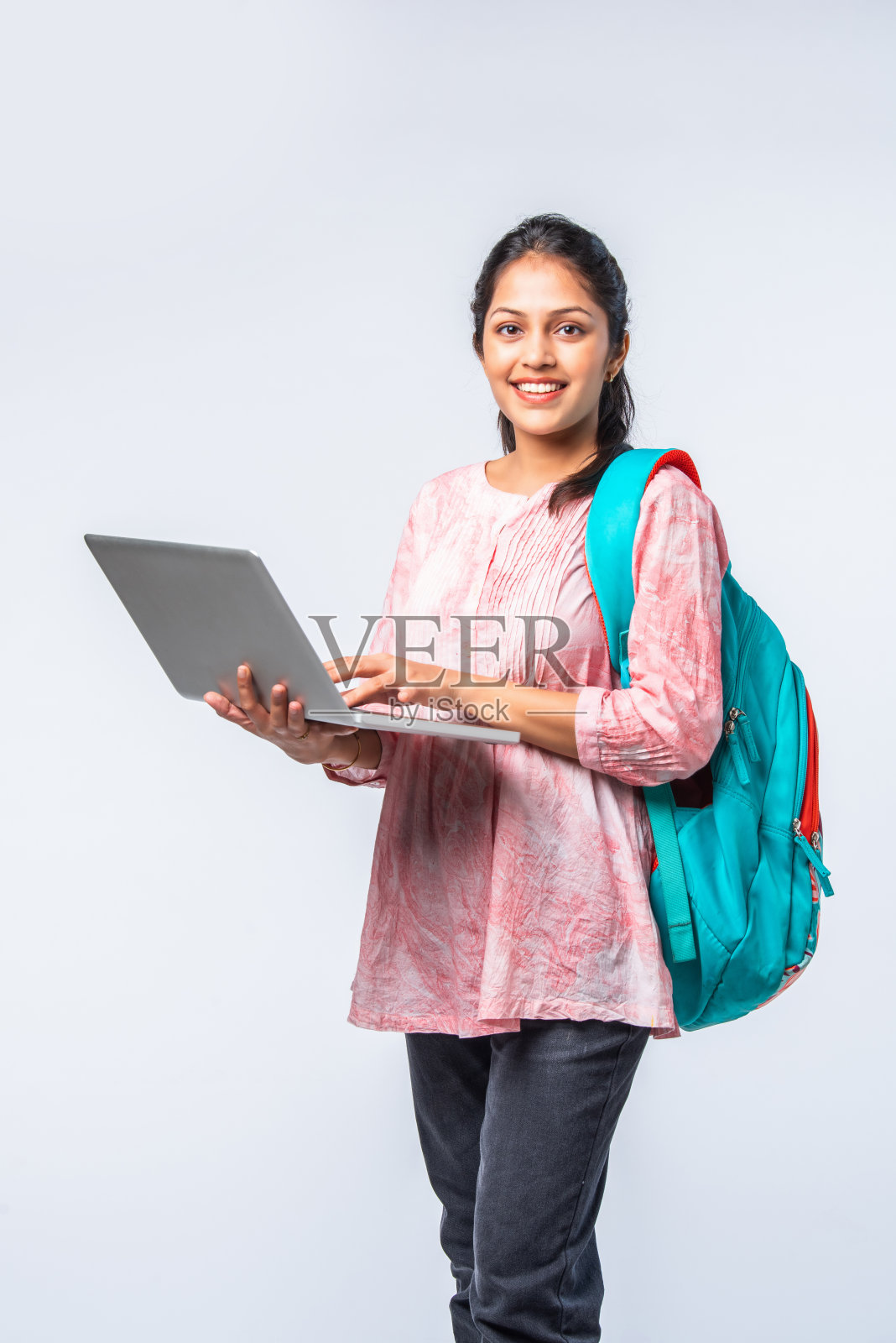 快乐的亚裔印度女大学生背着双肩包，手提电脑照片摄影图片