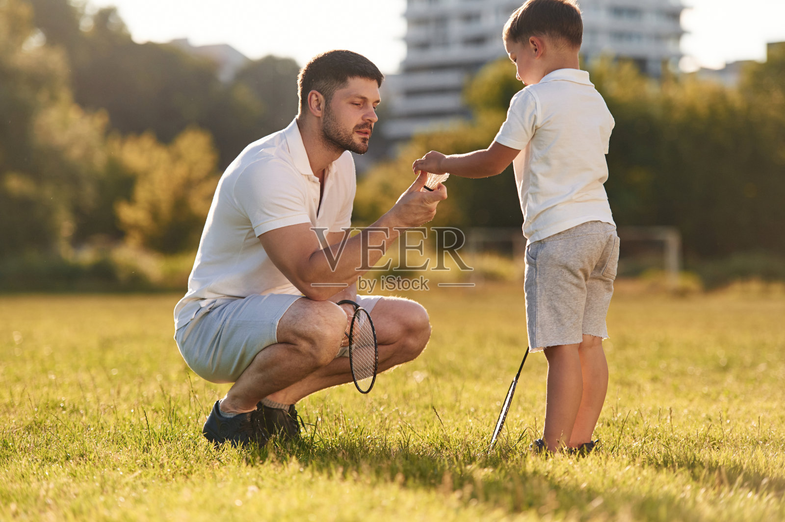 用羽毛球拍。父亲和小儿子一起在夏天的田野上照片摄影图片