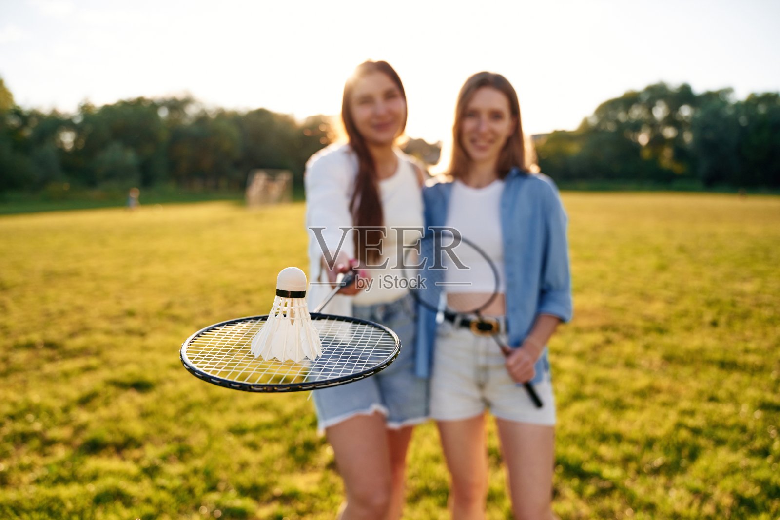 羽毛球在羽毛球拍上。两个女人在球场上玩得很开心照片摄影图片