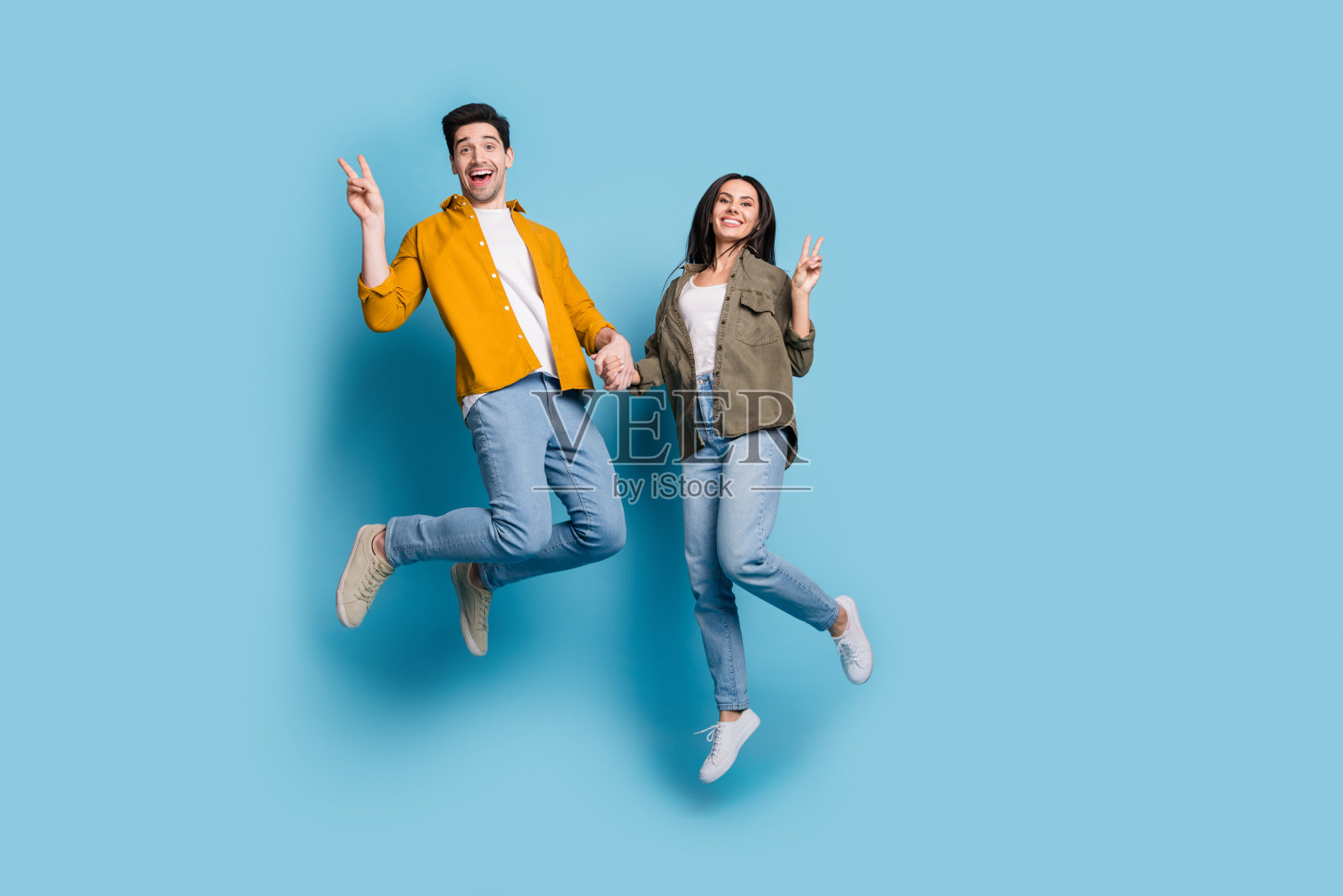 全身照片迷人的好心情女士男士穿衬衫跳高显示v字空间空旷孤立的蓝色背景照片摄影图片