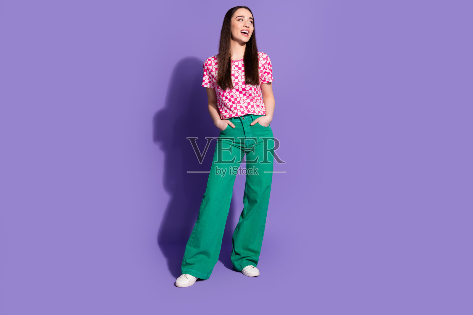 漂亮的年轻女子的全身肖像看起来空的空间穿格子t恤孤立的紫罗兰色背景照片摄影图片