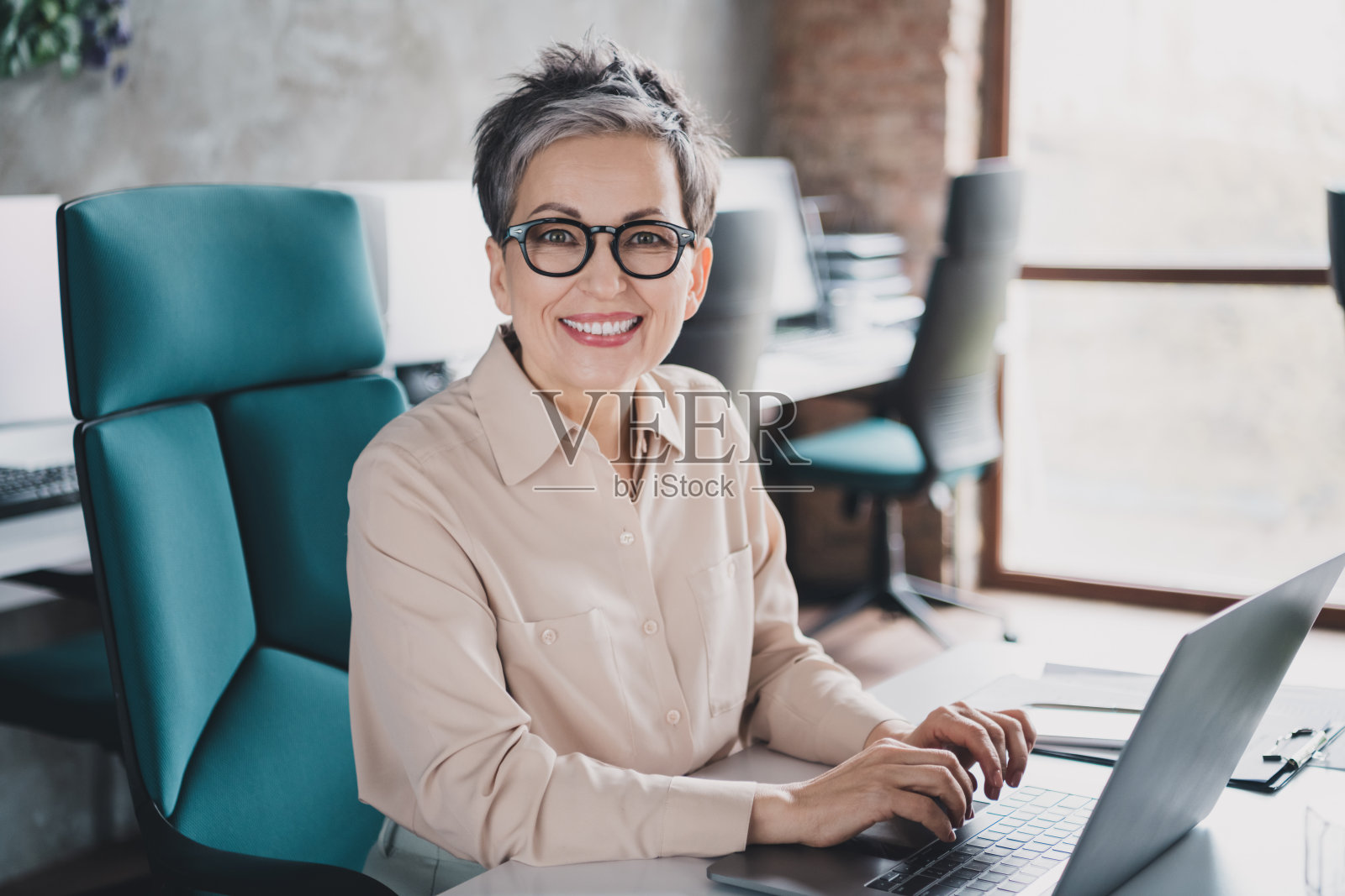 快乐迷人的高级女秘书穿着正装衬衫在室内车间工作站阁楼工作的现代设备照片照片摄影图片