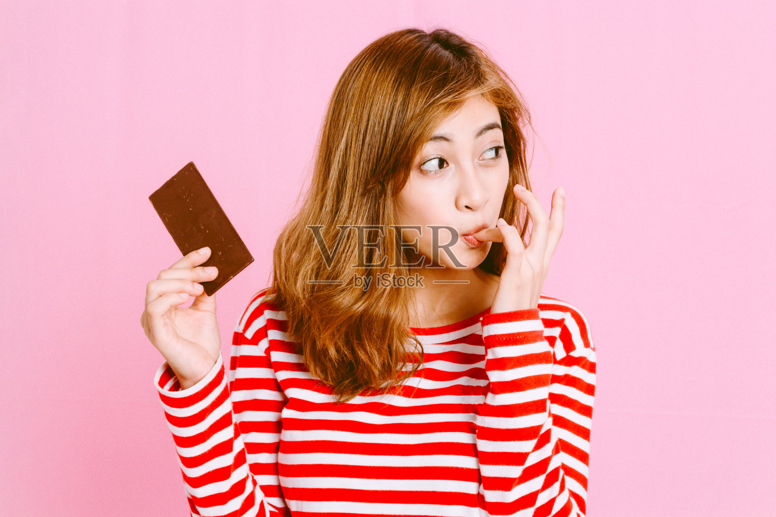 女人在粉红色的背景下舔手指照片摄影图片