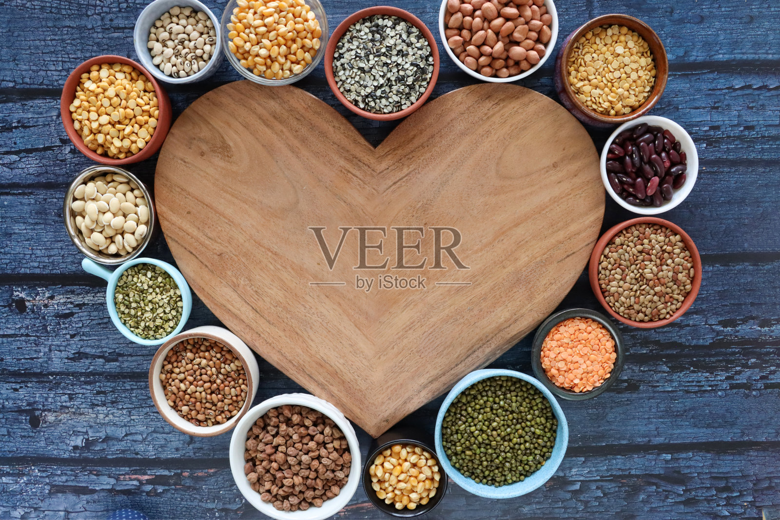图像的面包板和碗混合扁豆和豆类与复制空间，心形木制案板与选择干豆类在碗，促进健康食品，蓝色的木材背景照片摄影图片