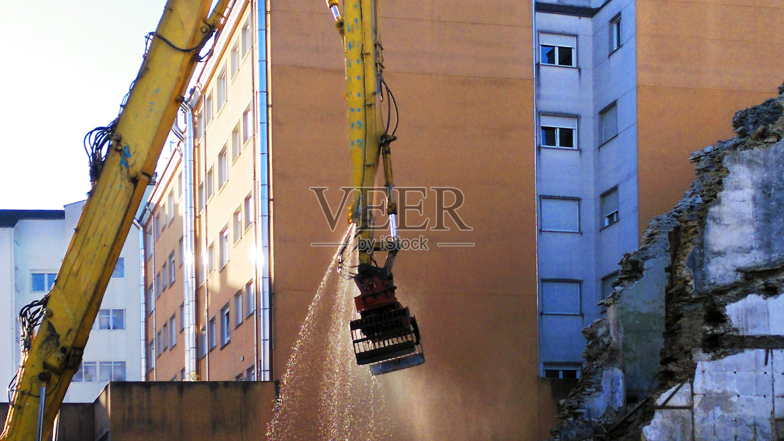 施工起重机在施工现场喷水，清除瓦砾。照片摄影图片
