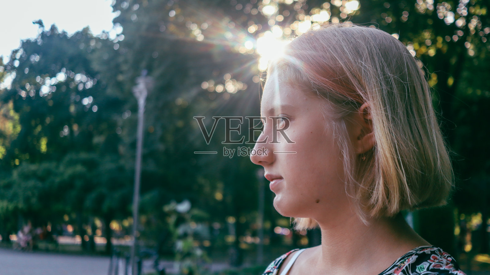 金发女孩坐在公园里，夕阳为背景照片摄影图片