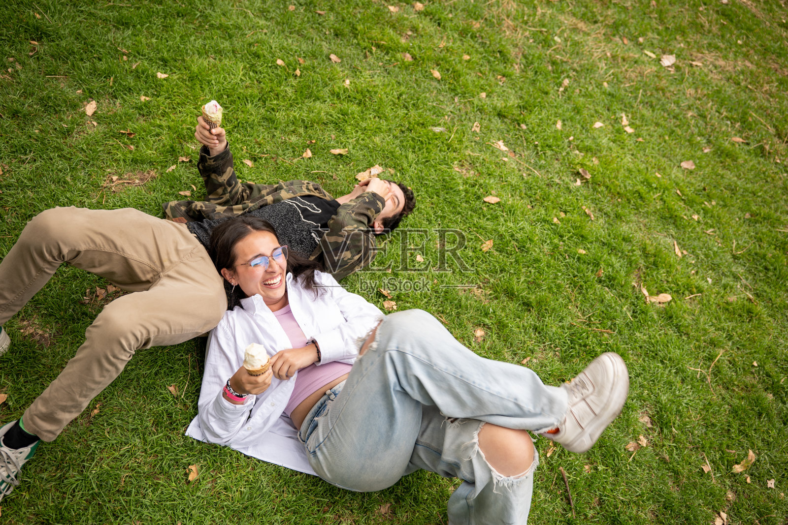 一个阳光明媚的日子里，年轻女子和年轻的z世代在一个绿色的公园里享受着冰淇淋照片摄影图片
