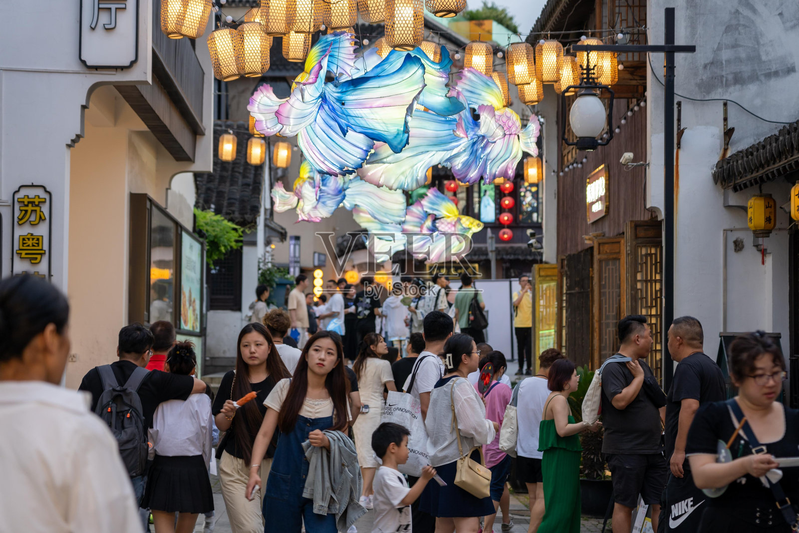 中国苏州一条熙熙攘攘的街道上挂满了五颜六色的灯笼和人群。照片摄影图片