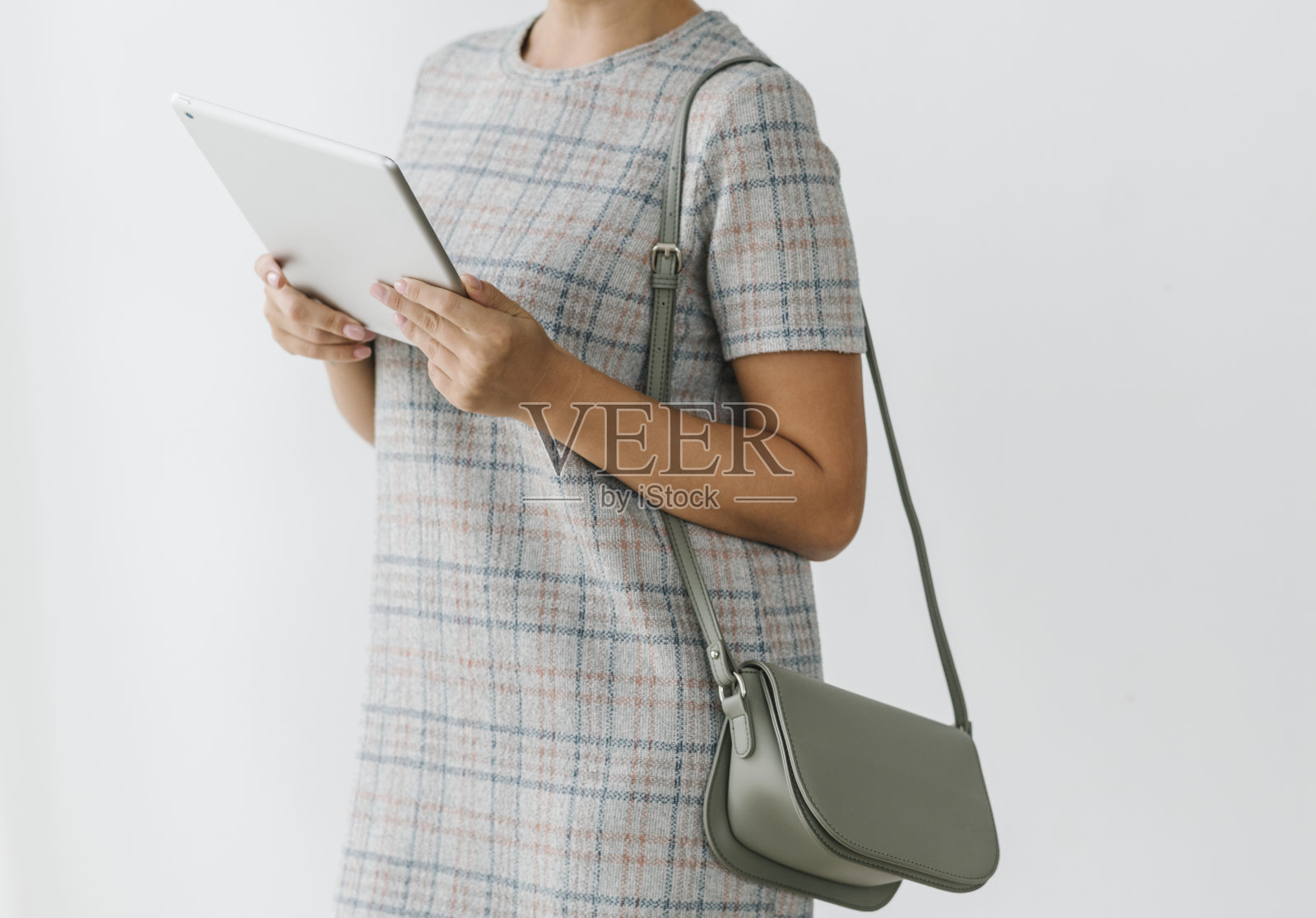 身穿灰色格子裙的女子正在使用平板电脑照片摄影图片