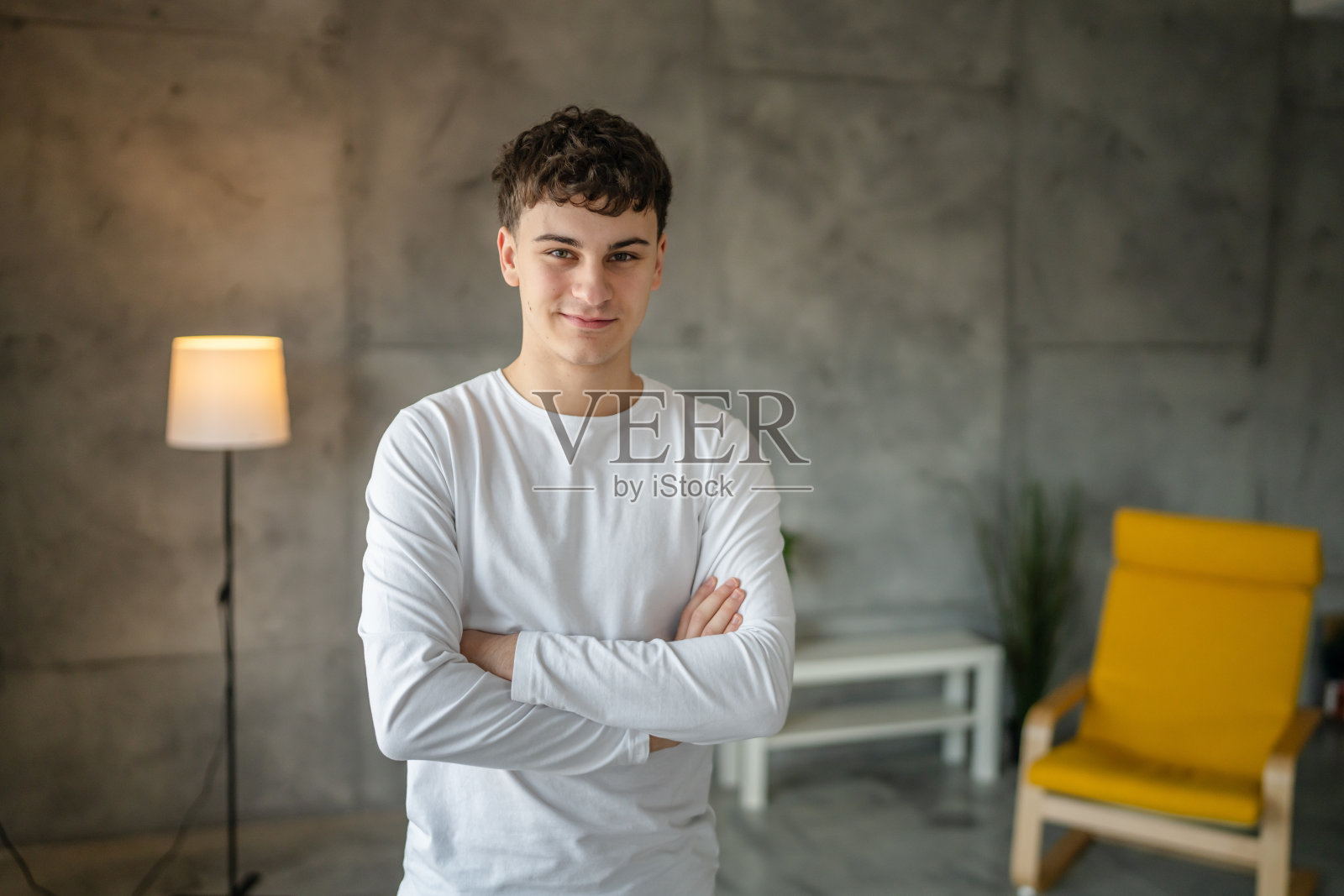 一名20岁的白人男子在家里微笑着看着镜头，穿着休闲的白衬衫照片摄影图片