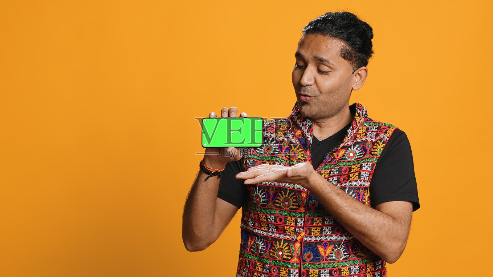 微笑的男子展示绿色屏幕的手机，工作室背景照片摄影图片