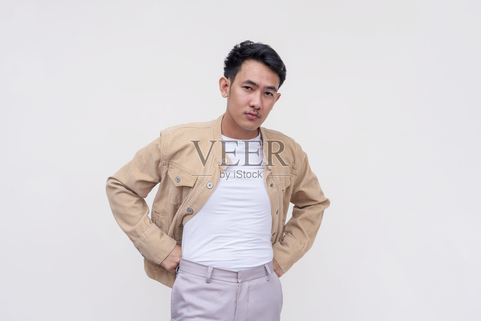 一个严肃而镇定的菲律宾人，穿着卡其布夹克和白衬衫，严肃地看着一个人，可能是一个陌生人。孤立在白色背景上。照片摄影图片