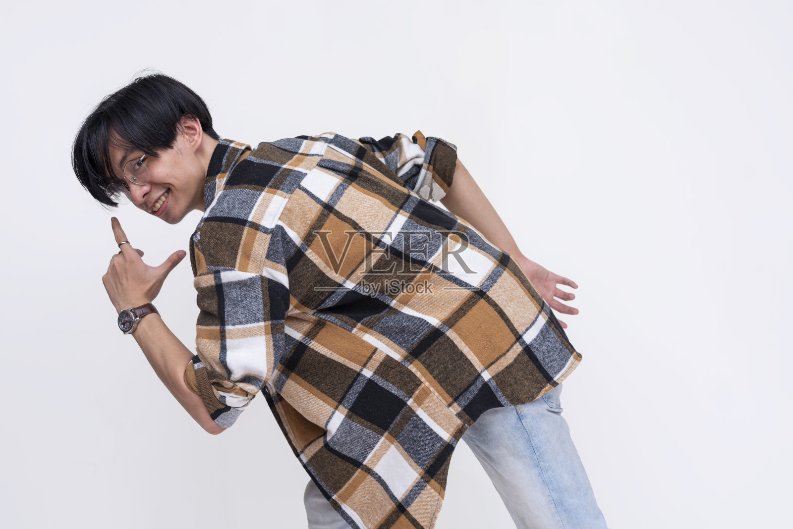 一个年轻的中国男子一边看着镜头，一边用夸张的方式逃跑。活跃的青少年在运动。孤立在白色背景下。照片摄影图片