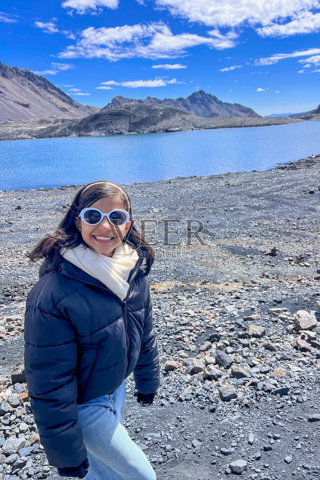 戴着太阳镜和黑色夹克的女人站在水边照片摄影图片