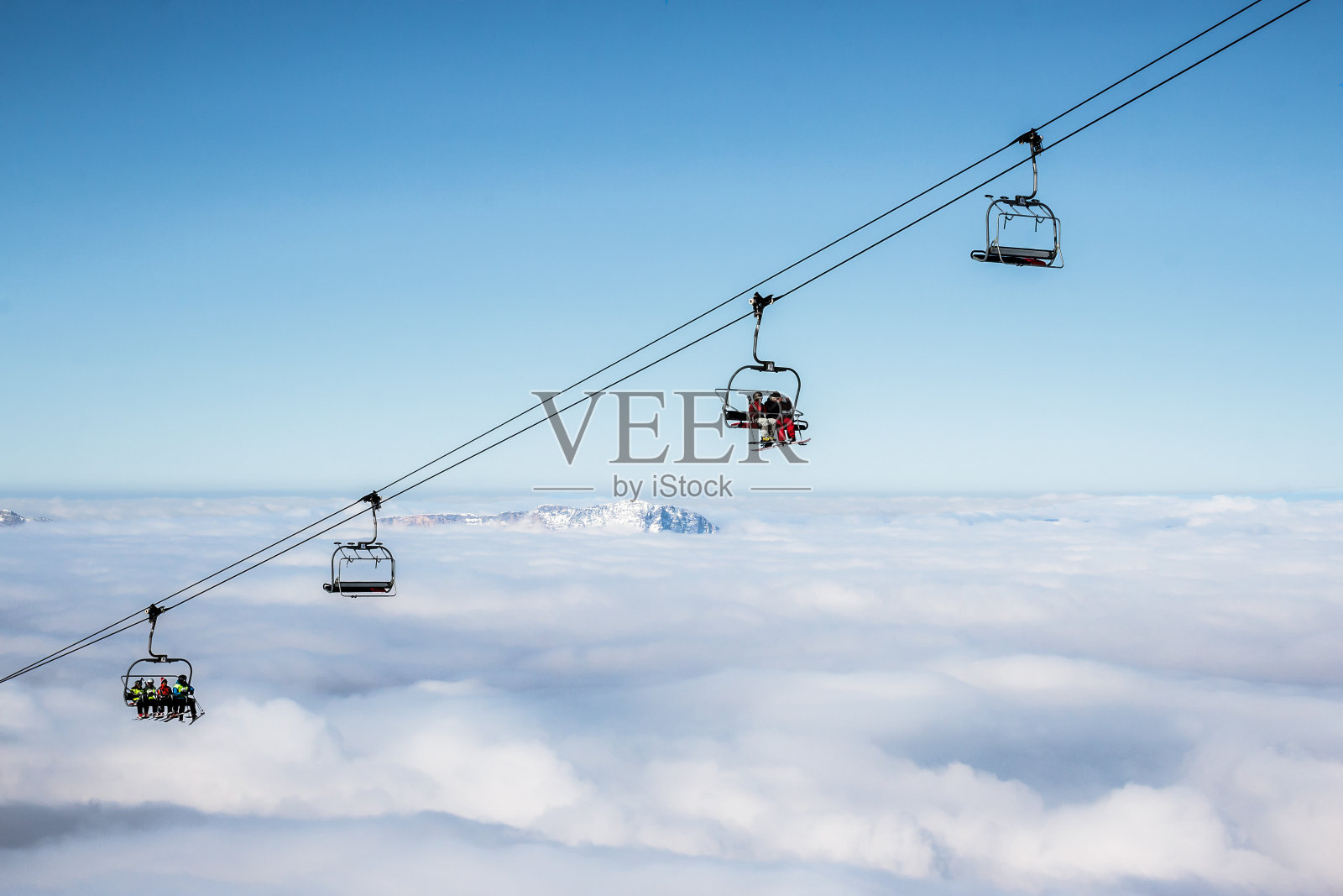 在晴朗的天空下，云景之上的滑雪缆车照片摄影图片