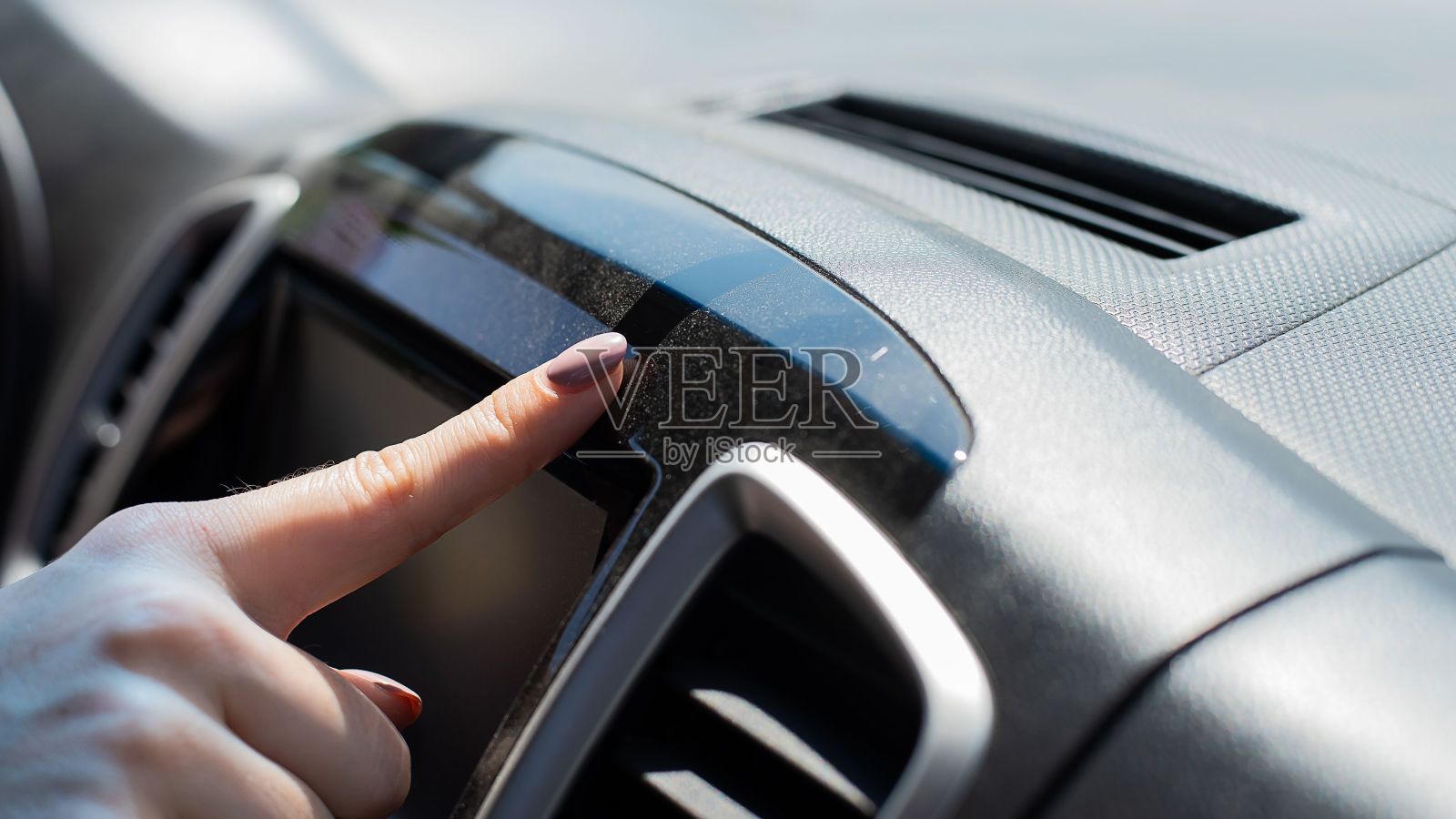 用手指擦去汽车仪表板上的灰尘。照片摄影图片