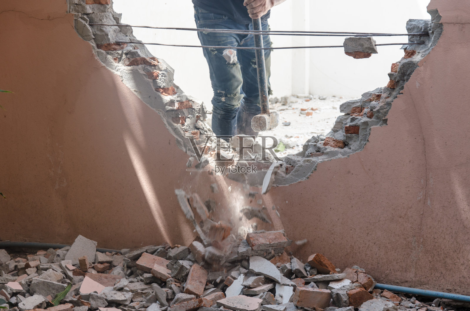 建筑工人用大锤拆除墙体的中段照片摄影图片