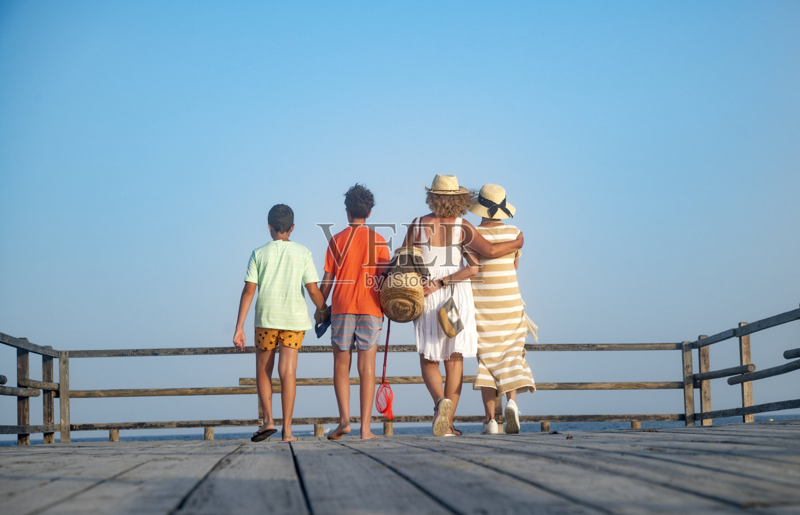 一家人一起走在木码头上，后景照片摄影图片