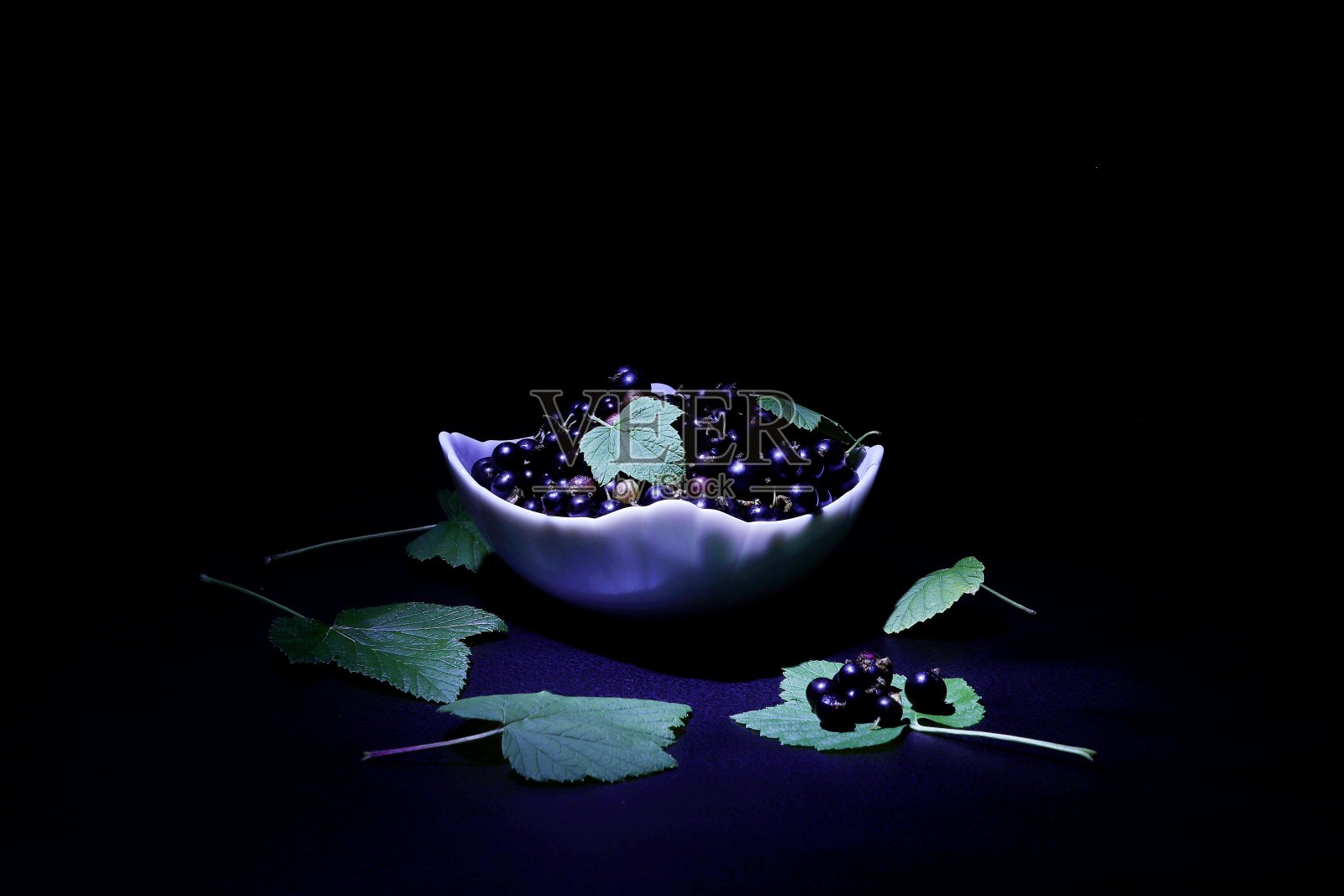 黑加仑水果在一个白色的碗在黑色的背景。照片摄影图片