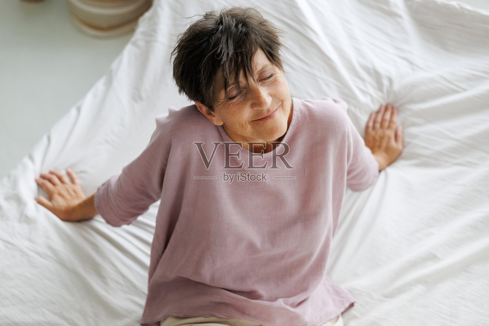 俯视图，微笑的成熟的女人在家里的床上放松照片摄影图片