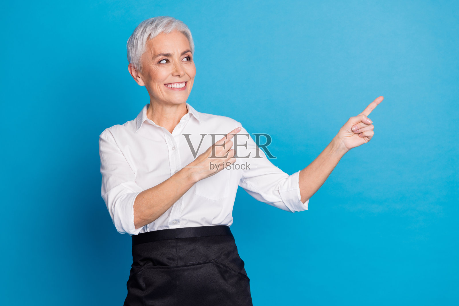 可爱的退休女士的照片为顾客服务咖啡店点看空空间穿着服务员制服孤立的蓝色背景照片摄影图片