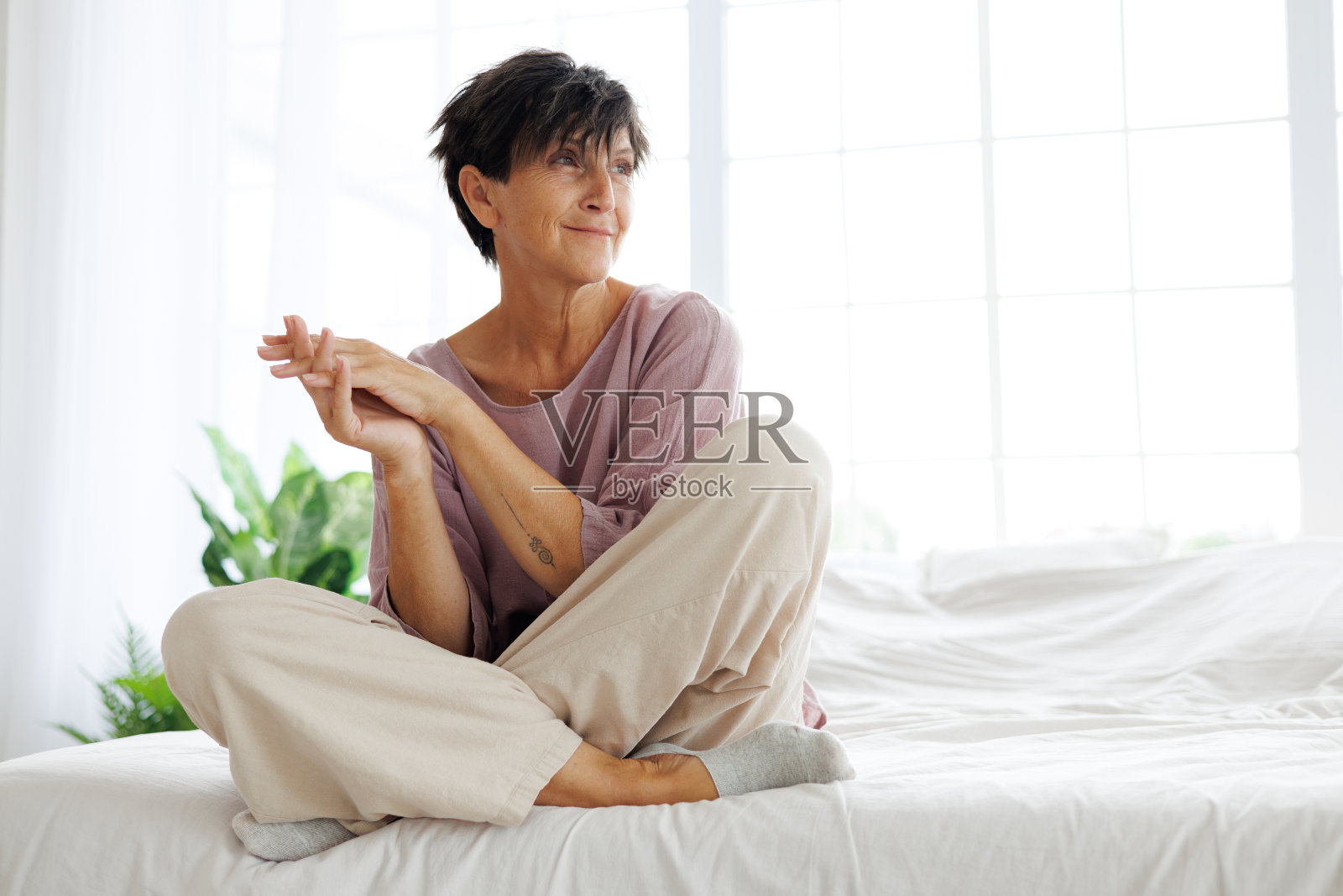 悠闲中年妇女身着亚麻服饰在家中床上照片摄影图片