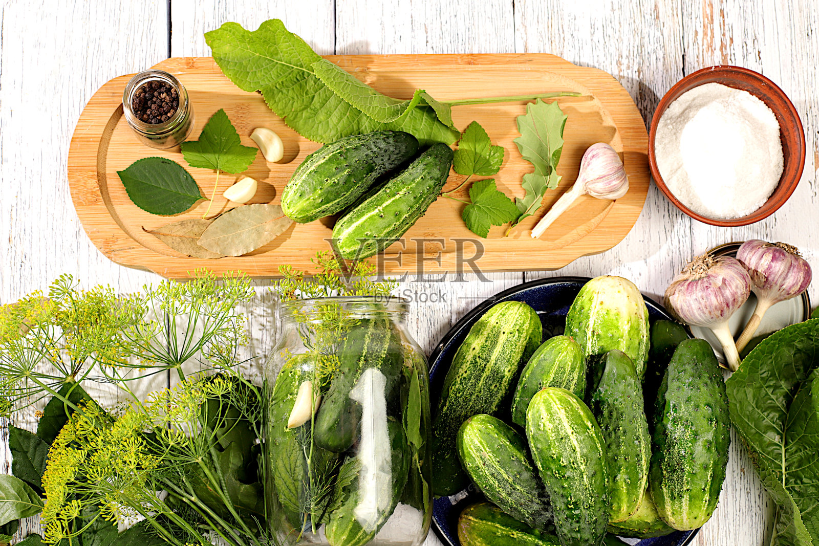 罐子里的新鲜黄瓜，厨房木桌上的香料，大蒜和叶子，自制酸洗食谱，乡村收获，黄瓜和酸洗材料，家庭罐头概念。照片摄影图片