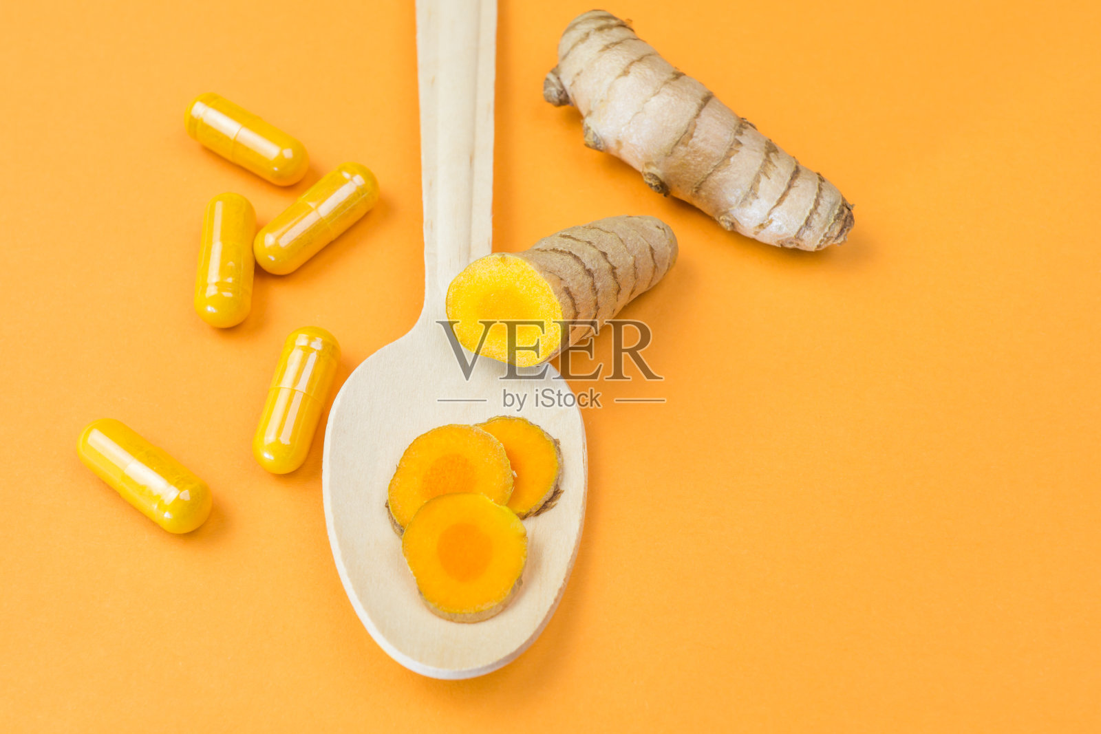 正上方拍摄的姜黄根和黄色背景的胶囊照片摄影图片