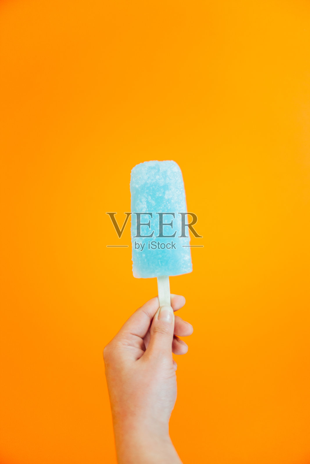 橙色背景下手持冰淇淋的特写照片摄影图片