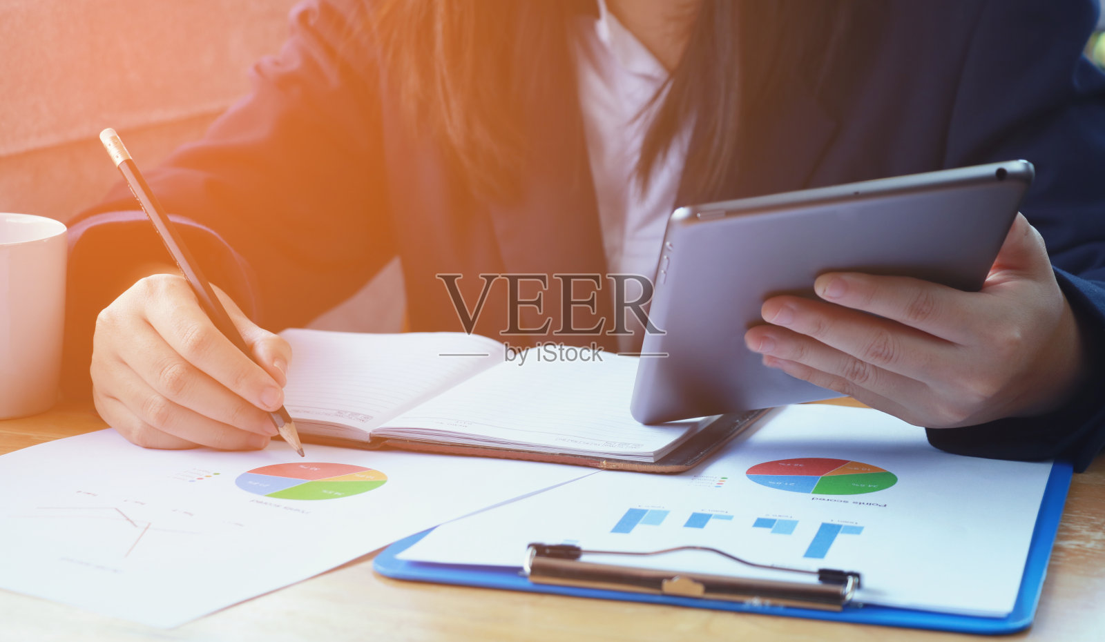 女商人使用数码平板电脑，分析桌上的文件照片摄影图片